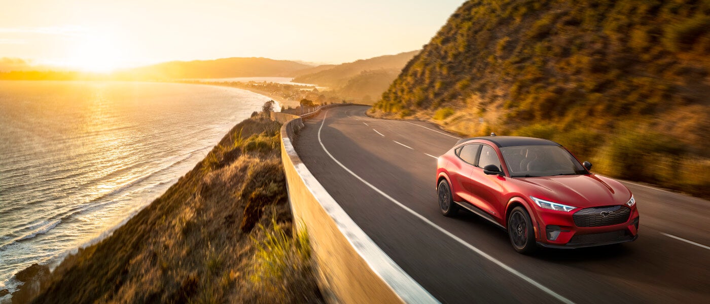 2025 Ford Mustang Mach-E Exterior Driving Down Seaside Road At Sunrise